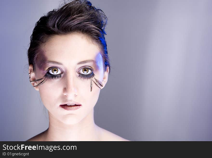 Attractive young lady with extravegant makeup and eyelashes with plain background