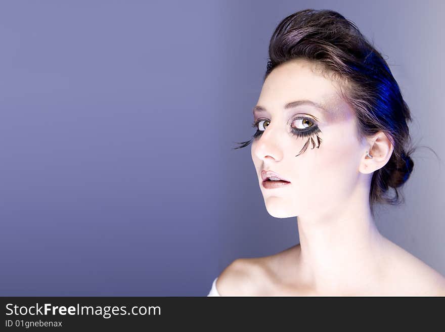 Attractive young lady with extravegant makeup and eyelashes head tilted to side