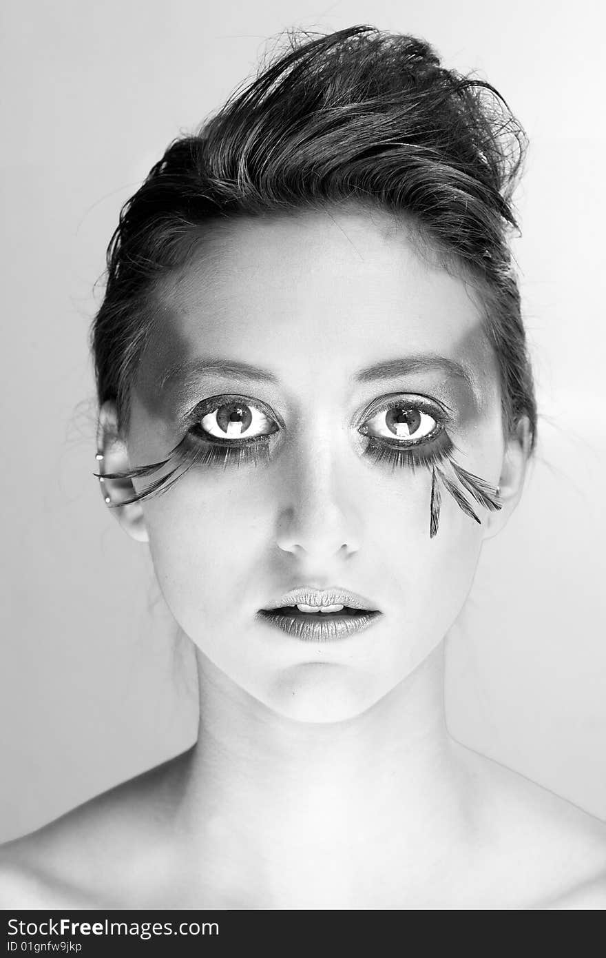 Attractive young lady with extravegant makeup and black eyelashes black and white background with some gray