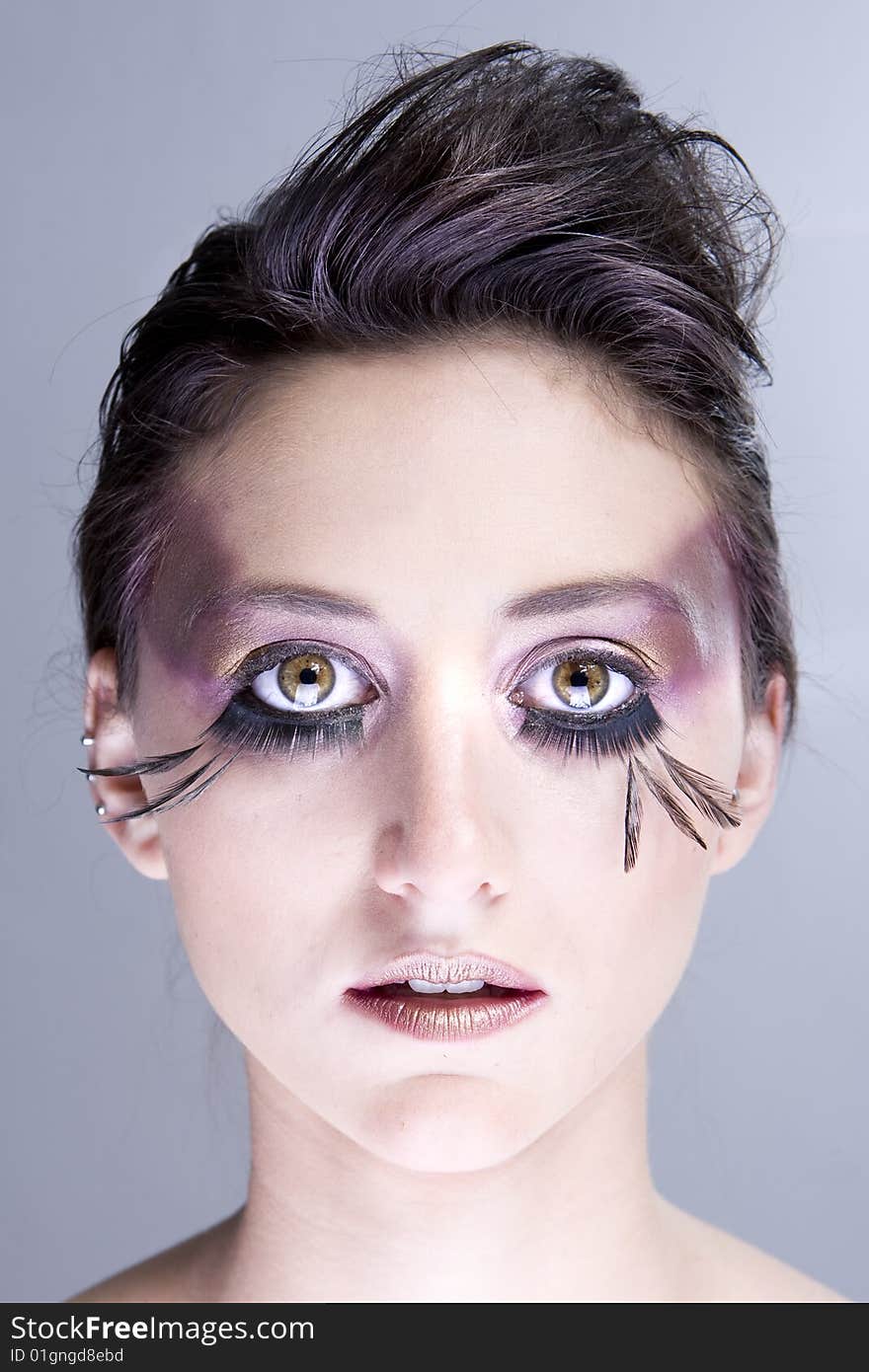 Attractive young lady with extravegant makeup and black eyelashes black and white background with some gray