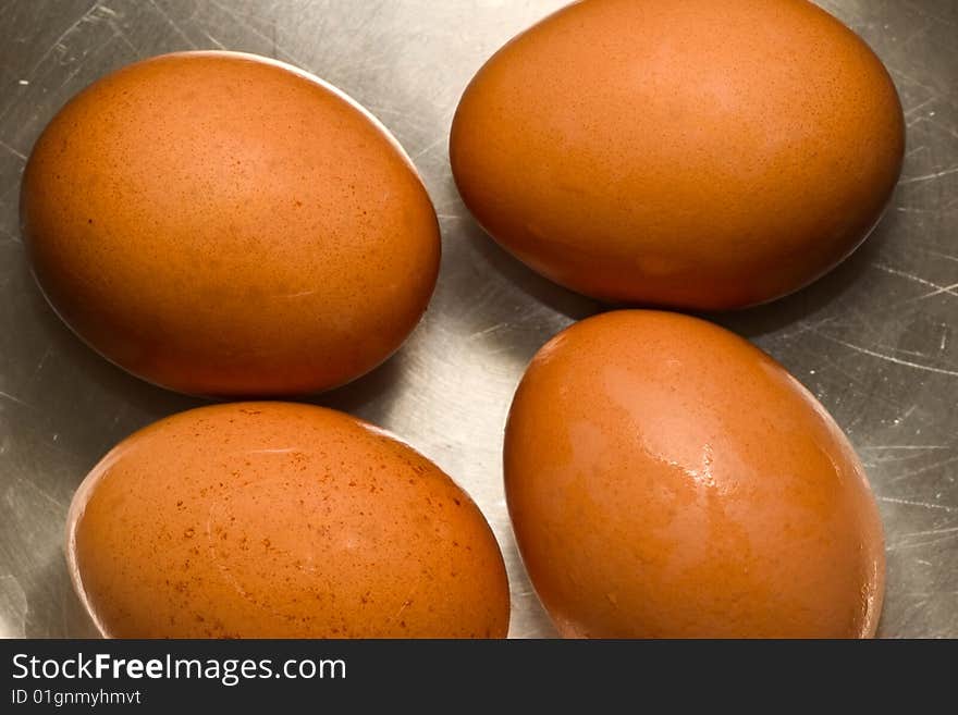 Four brown eggs on scratched metallic surface