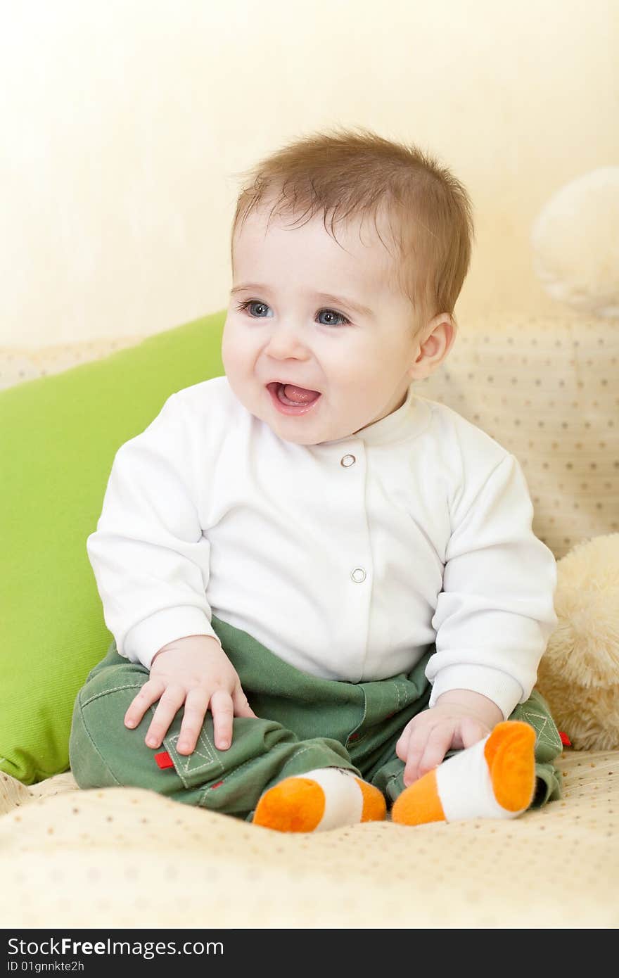 Portrait of adorable happy blue-eyes baby sitting on sofa. Portrait of adorable happy blue-eyes baby sitting on sofa