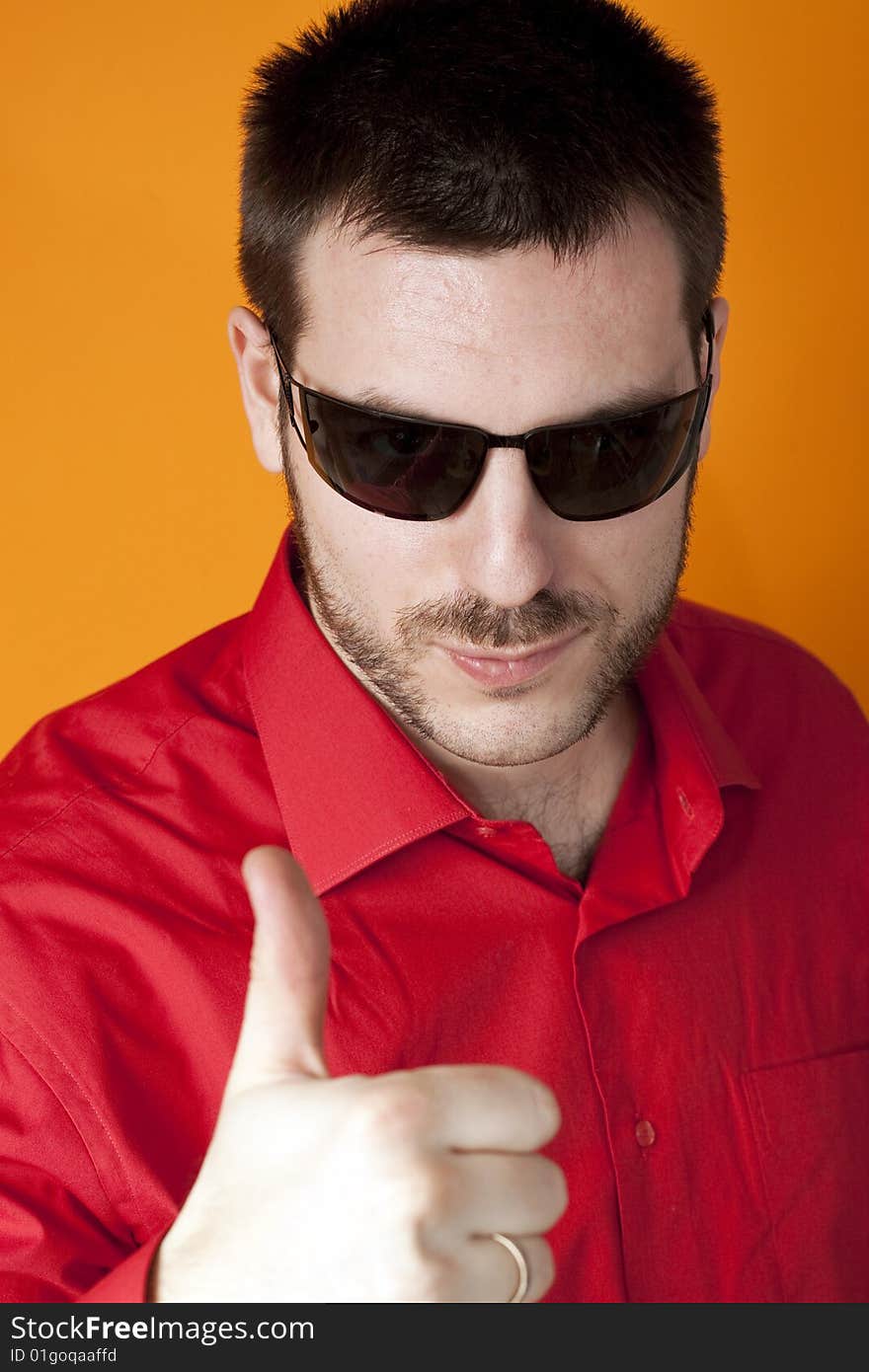 Young, handsome man, wearing sunglasses, holding his thumb up, smiling. Young, handsome man, wearing sunglasses, holding his thumb up, smiling