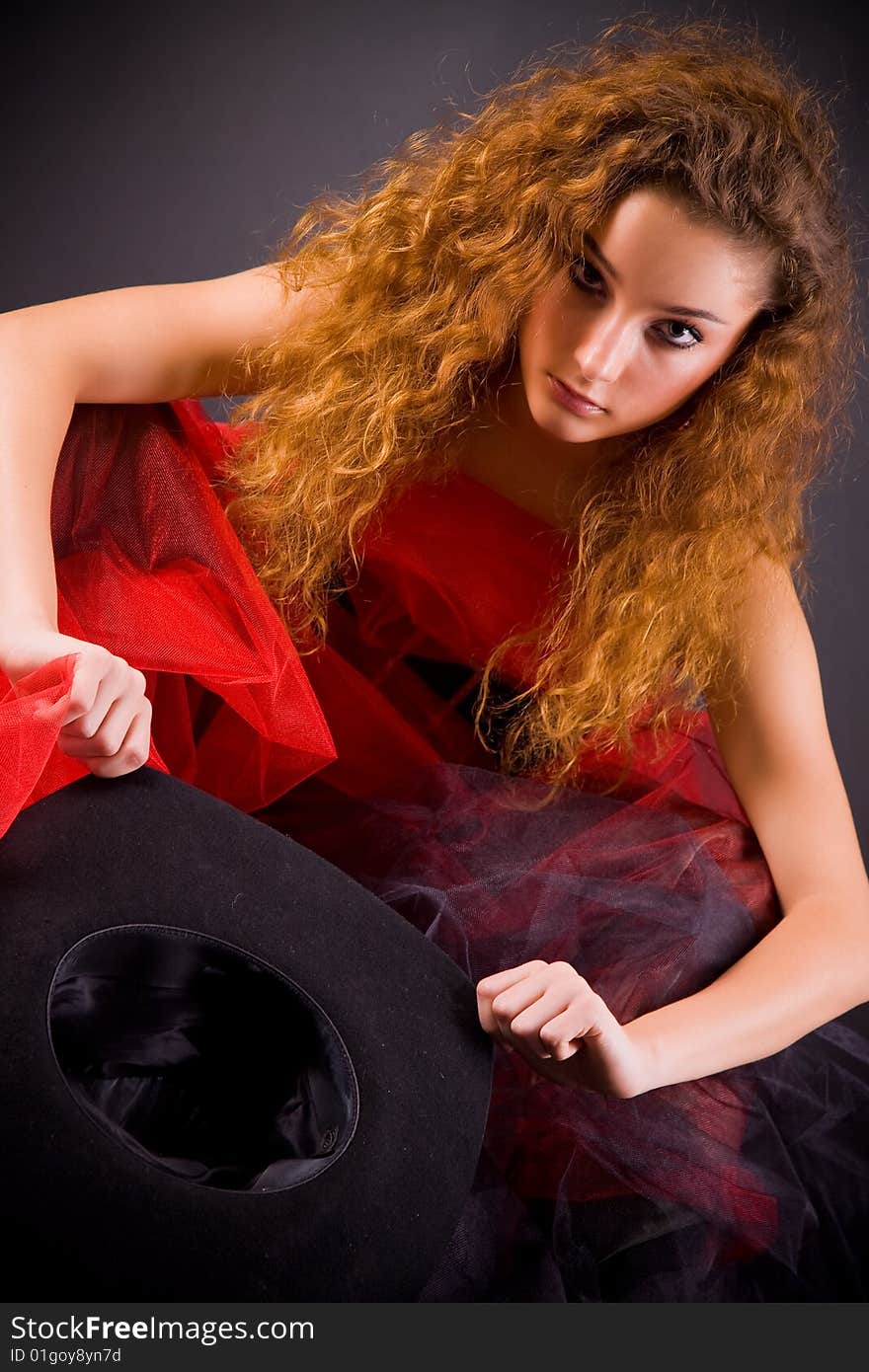 Red-haired girl holding hat over dark background