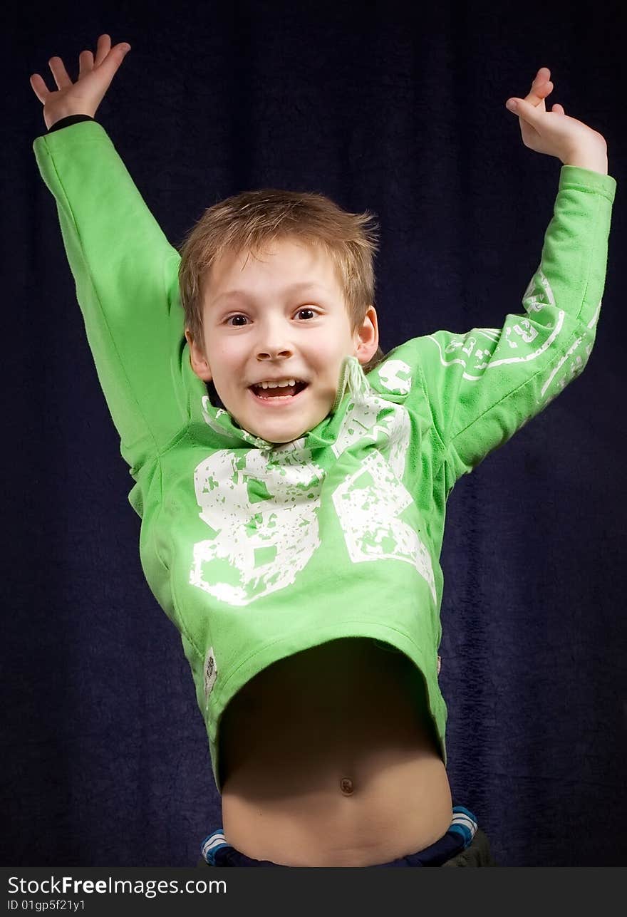 Boy jumps having extended both hands on turn blue background. Boy jumps having extended both hands on turn blue background