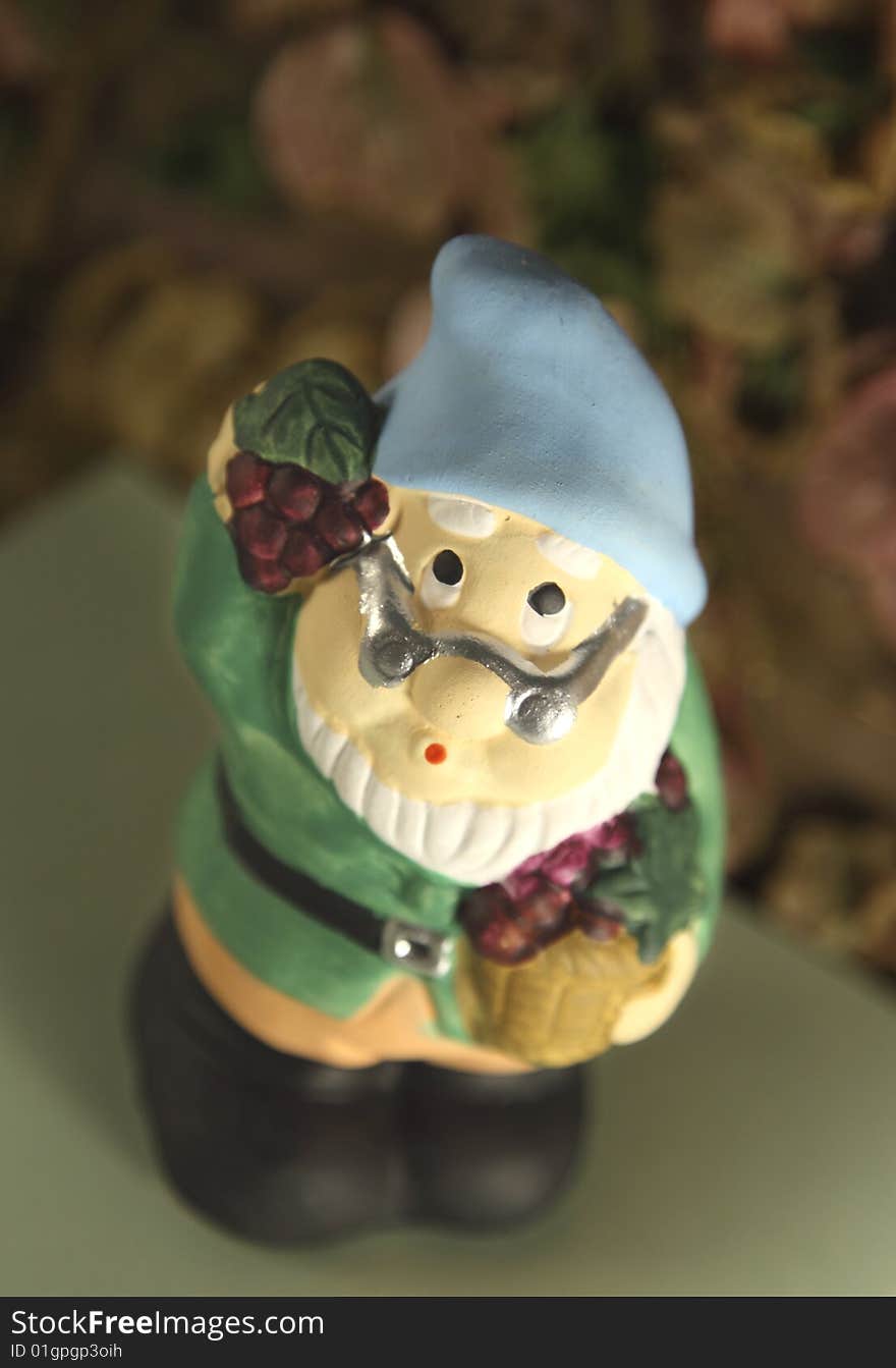 Clay gnome holding a basket and a bunch of grapes. Clay gnome holding a basket and a bunch of grapes