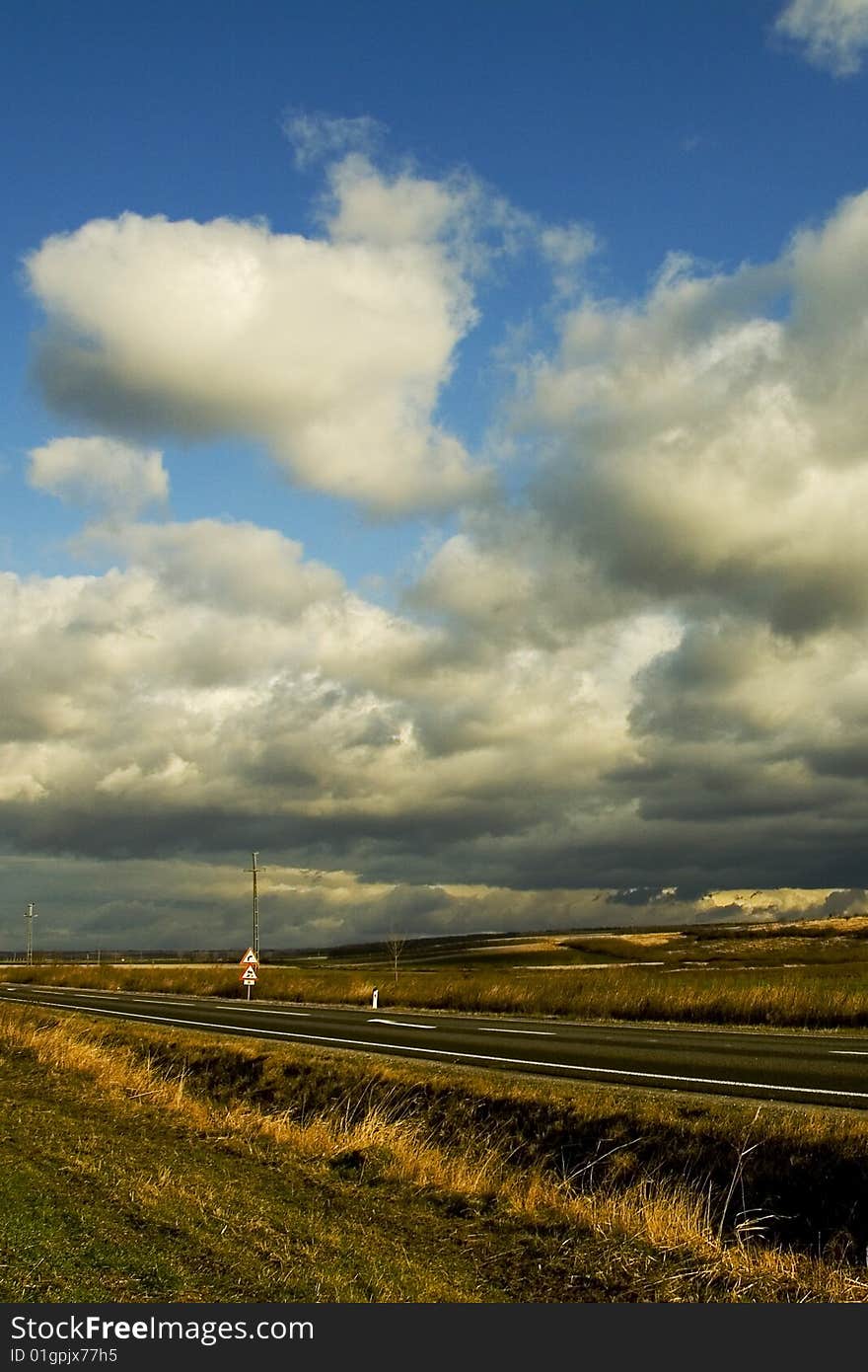 Image of a an empty road and blue sky and clouds. Image of a an empty road and blue sky and clouds