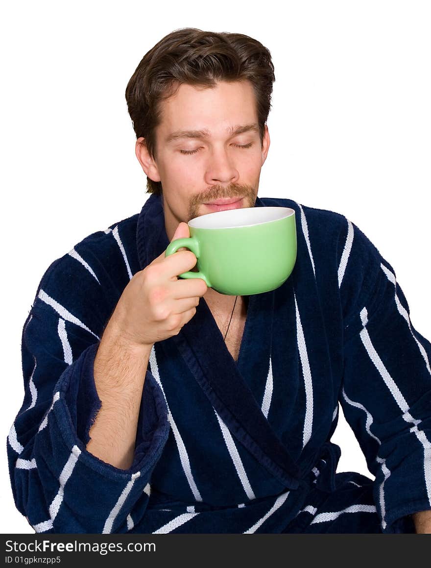 Young man in bathrobe drinks tea isolated