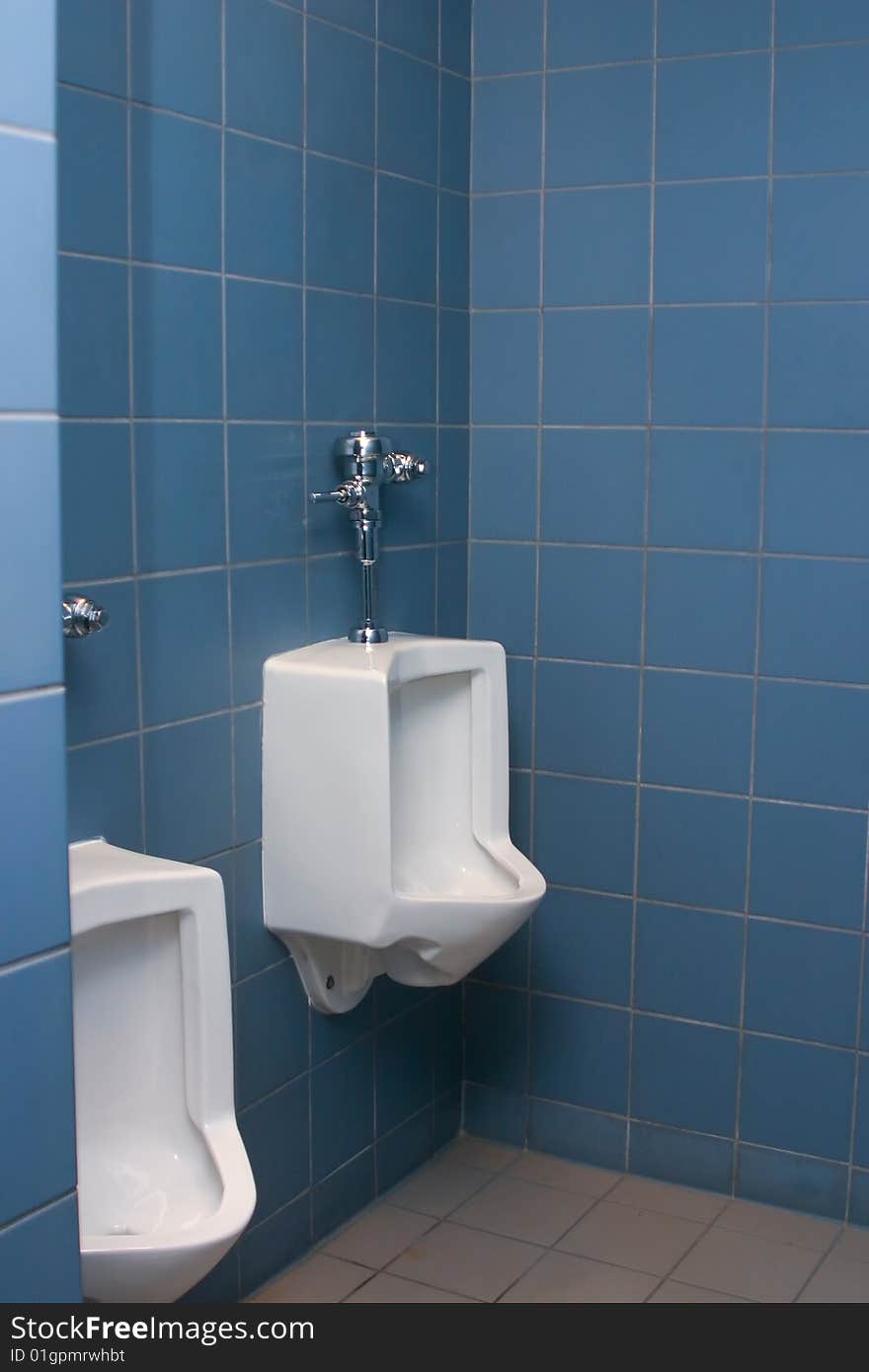 Urinals in the men's room with blue tiles on the wall