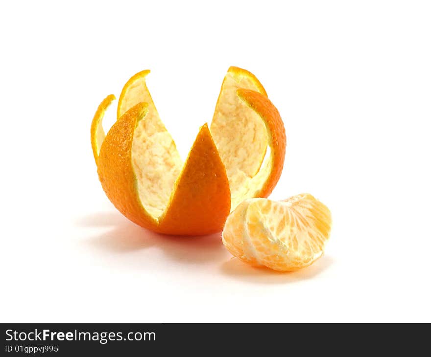 Tangerine peel cut out in the form of a crown and a tangerine segment isolated on a white background. Tangerine peel cut out in the form of a crown and a tangerine segment isolated on a white background