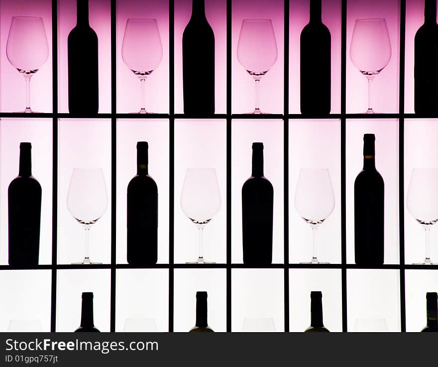 Black bottles and crystal glasses decorate a wall creating a motif