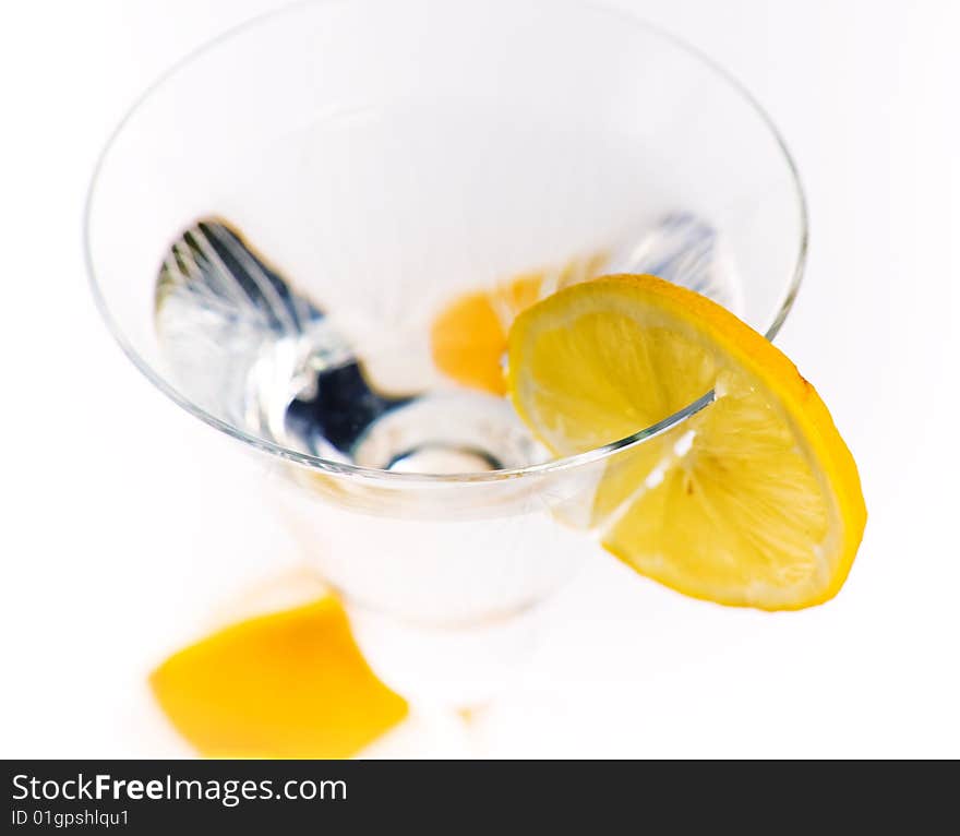Transparent glass with a liquid, a segment of a lemon and the cut lemon at the glass basis. Transparent glass with a liquid, a segment of a lemon and the cut lemon at the glass basis.