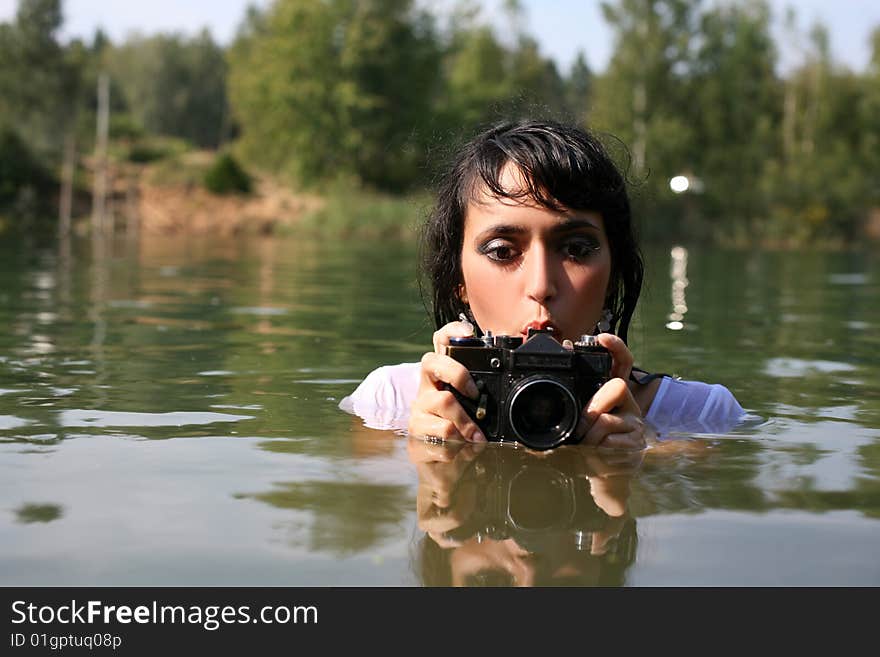 Lovely girl photographer in water in summertime