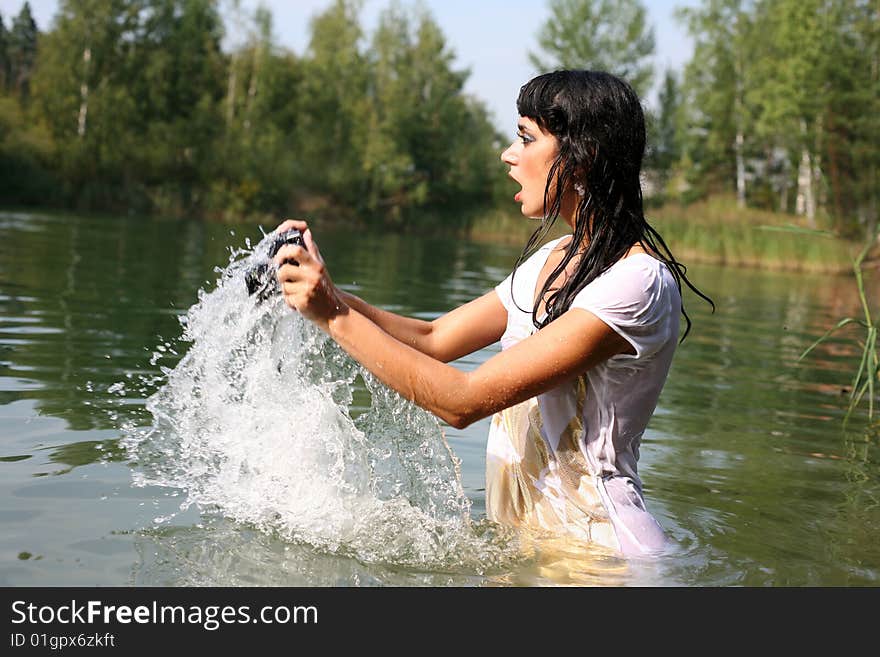 Lovely girl photographer in water in hot summertime