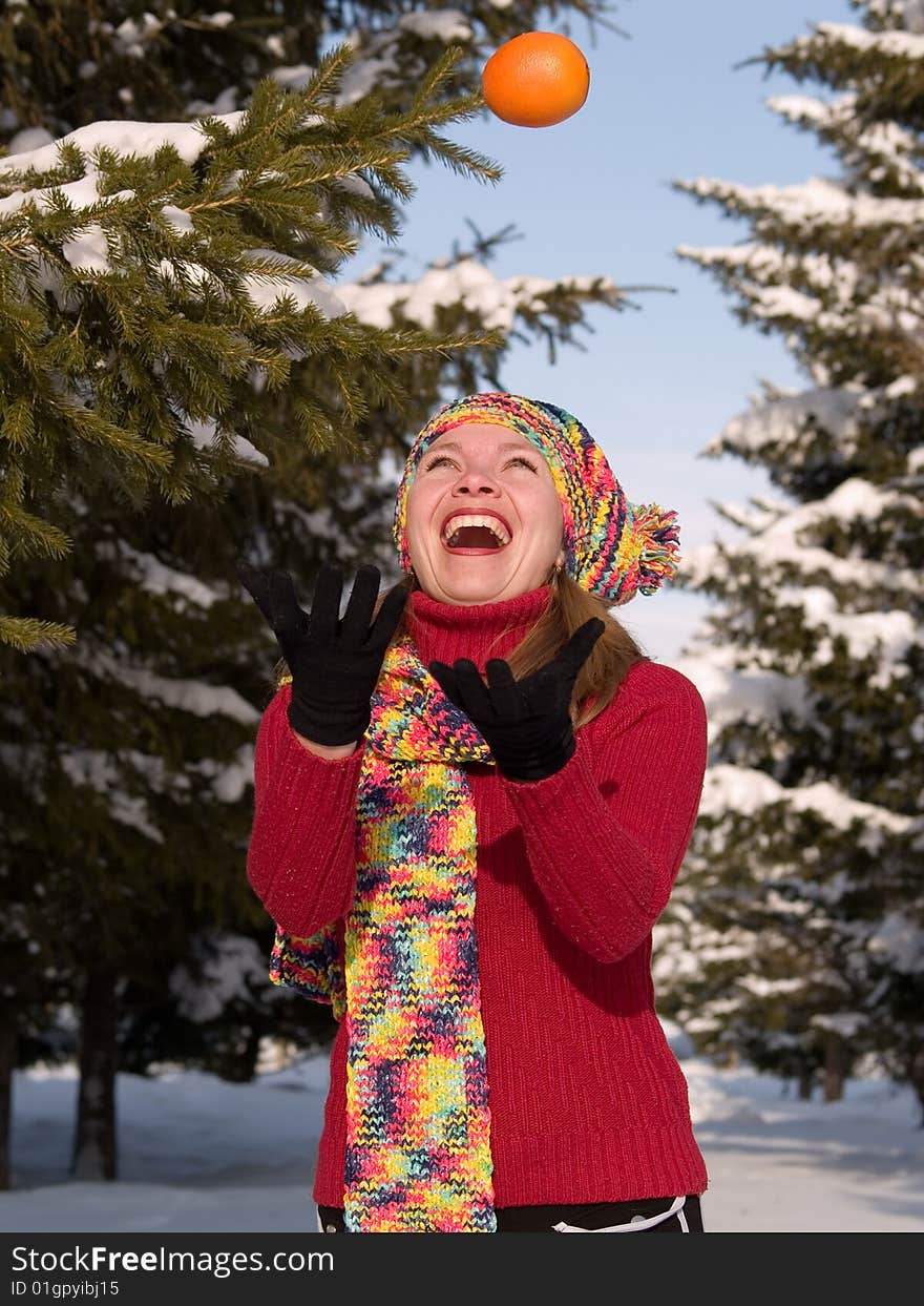 Girl throws orange amongst fir trees