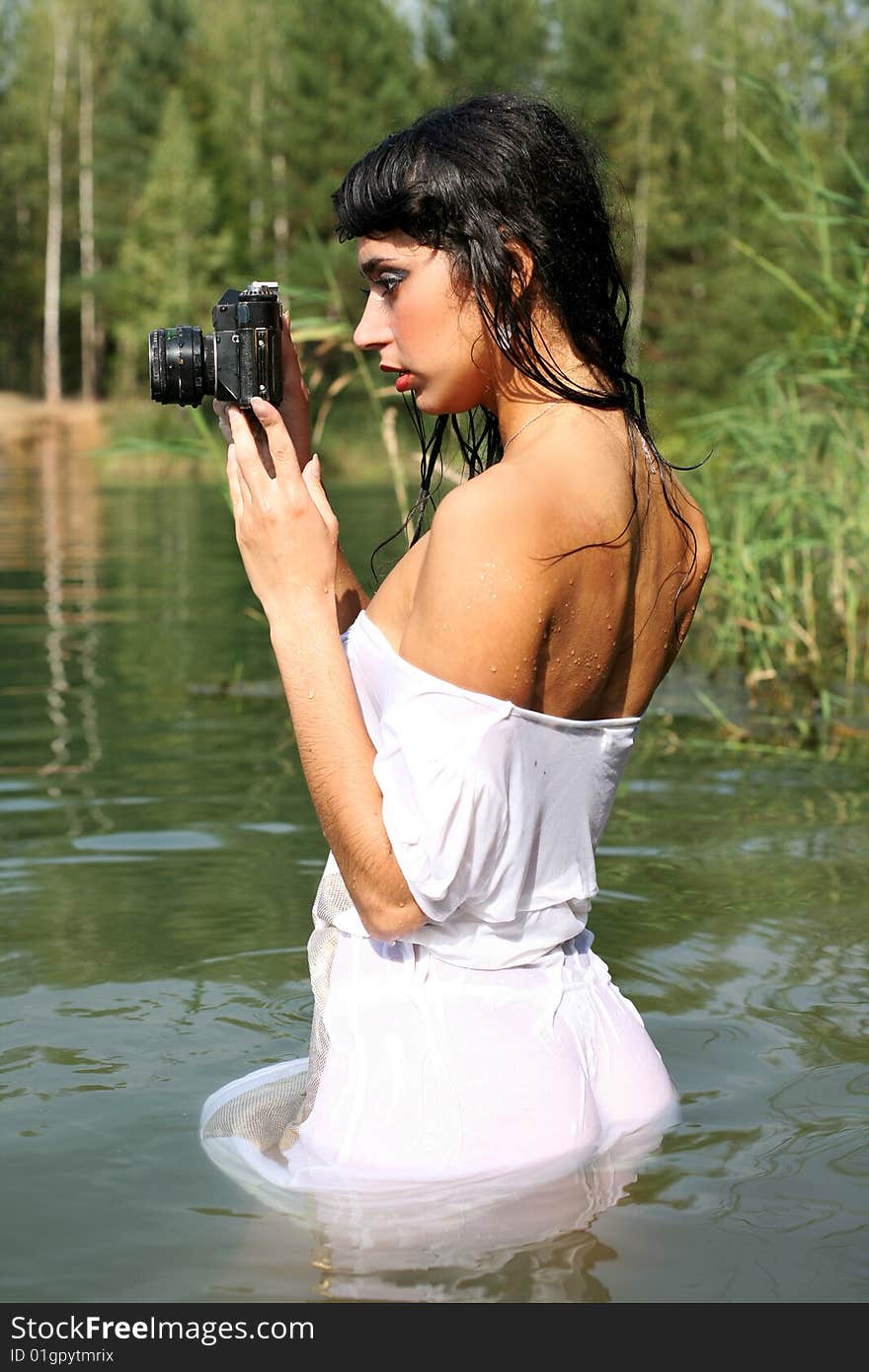 Lovely brunette girl photographer in water in hot summertime