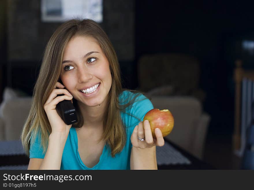 Beautiful young woman talks on the telephone while eating an apple at home. Beautiful young woman talks on the telephone while eating an apple at home.