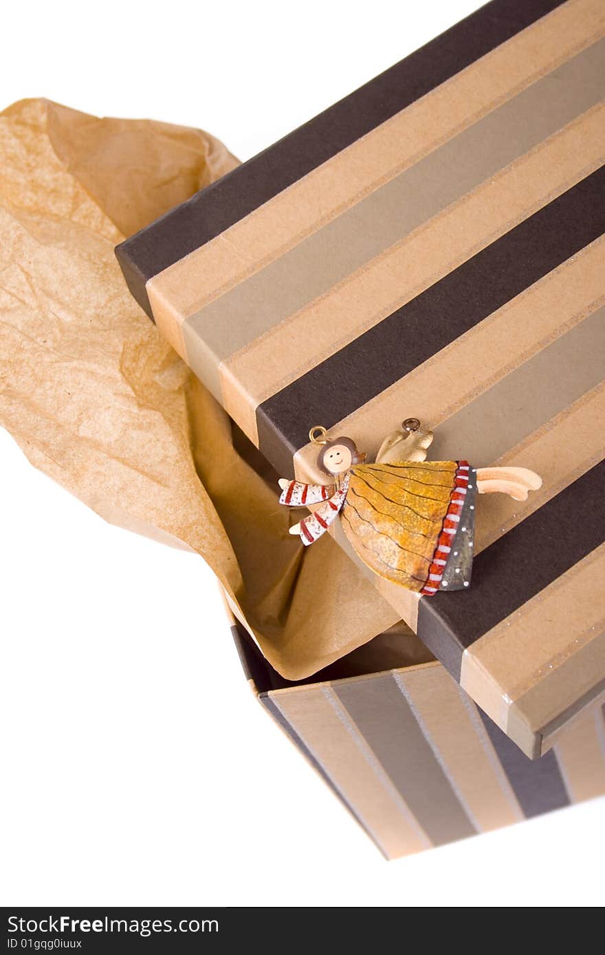 Closeup of opened gift box with craft paper inside and decorative angel