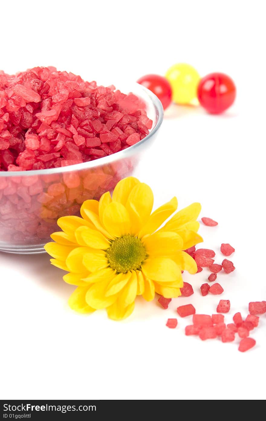 Spa pruducts: bath salt, oil balls in a bowl and yellow flower