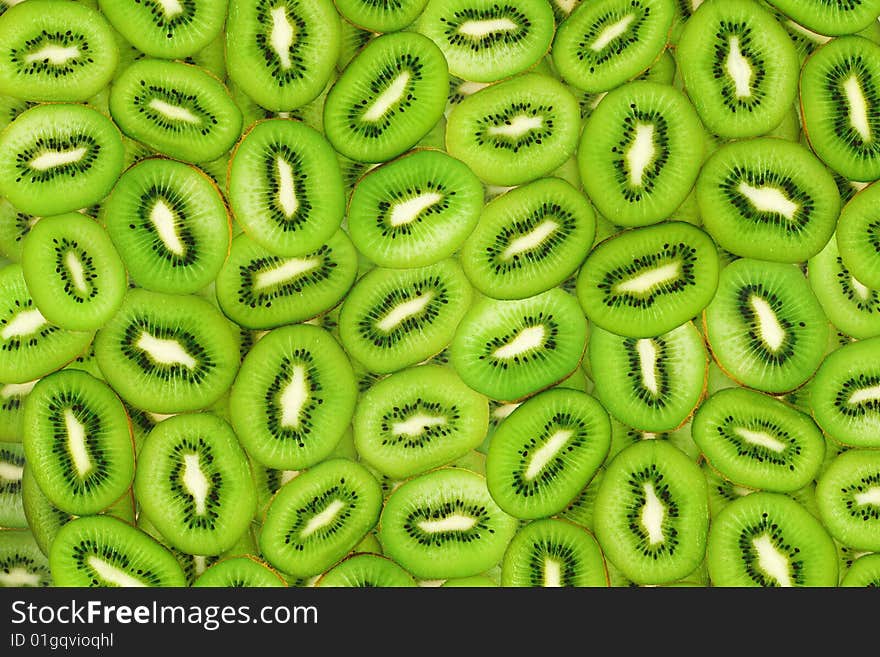 Sliced green kiwi fruit in the form of background. Sliced green kiwi fruit in the form of background