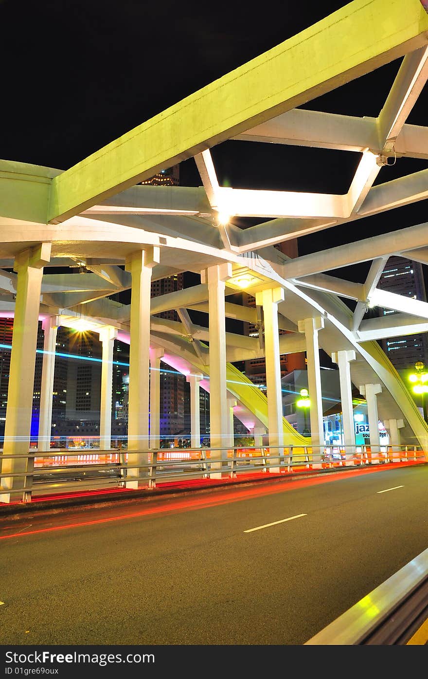 A view of a bridge with cars zooming past at night, and the central business district in the background. A view of a bridge with cars zooming past at night, and the central business district in the background.