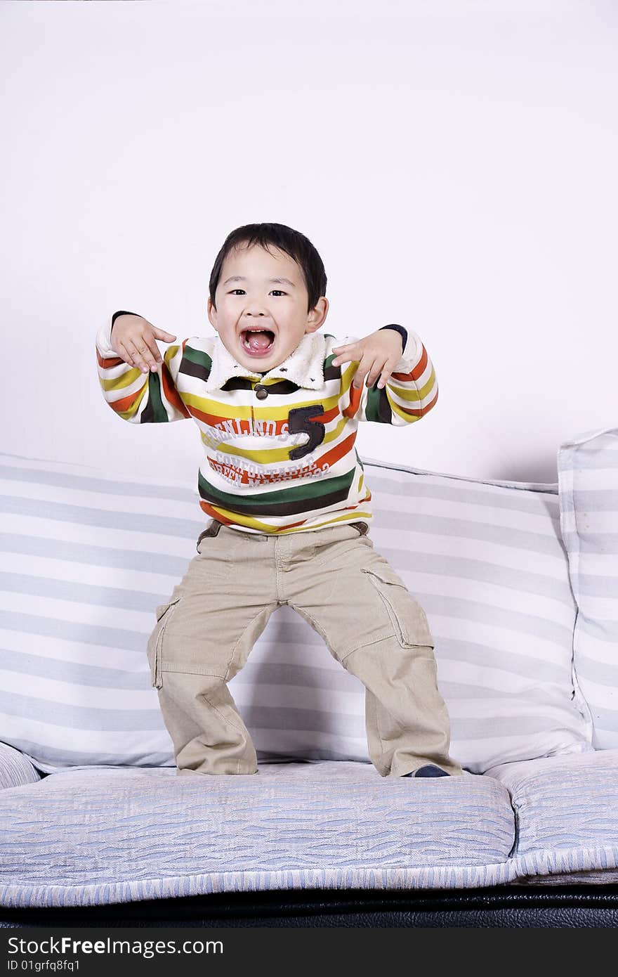 A picture of a little chinese boy playing roles and having great fun on sofa at home