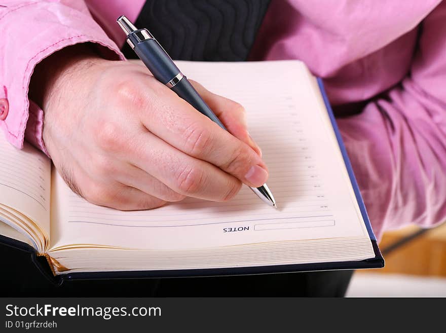 Closeup of a businessman hand writing a note on a agenda book. Closeup of a businessman hand writing a note on a agenda book