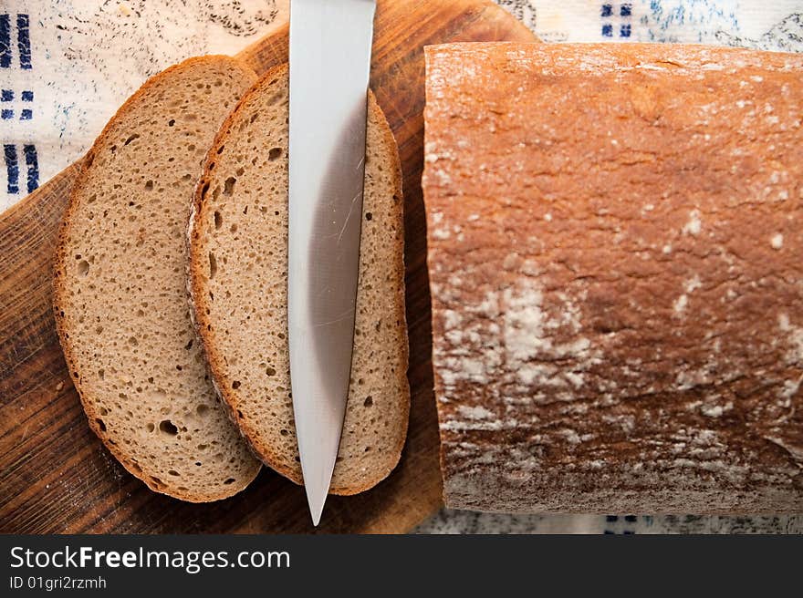 Pieces of bread on breadboard with knife.