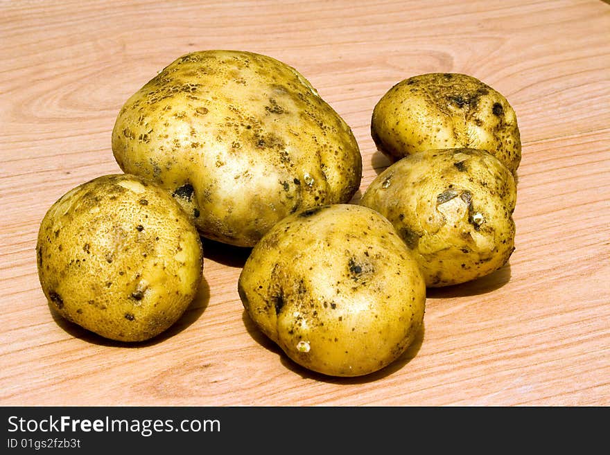 Raw potatoes of various sizes on a wooden table. Raw potatoes of various sizes on a wooden table