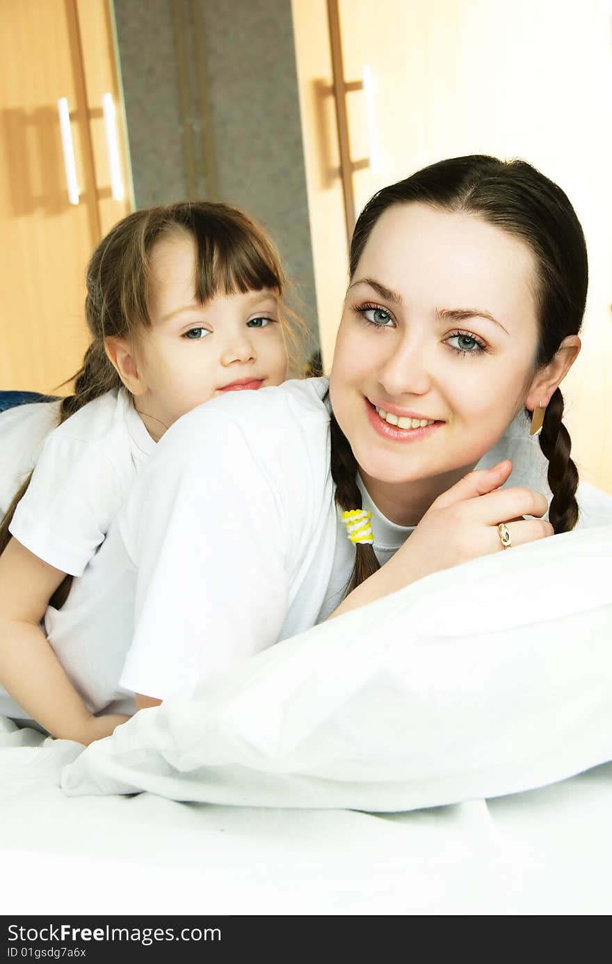 Young beautiful mother with her little daughter on the bed at home. Young beautiful mother with her little daughter on the bed at home