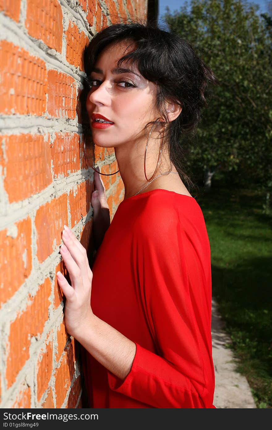 Lovely girl beside wall in red dress