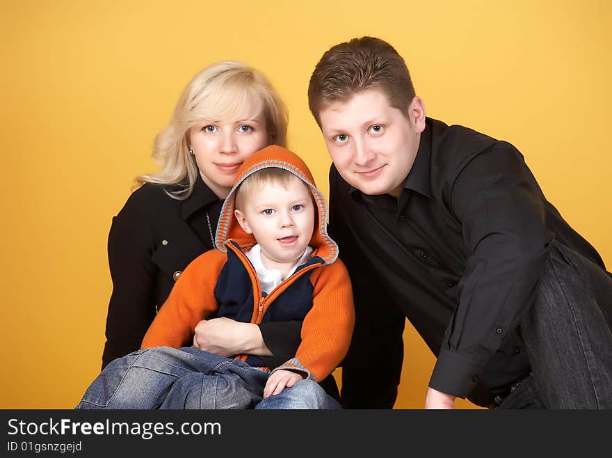 Happy family with baby on yellow background. Happy family with baby on yellow background