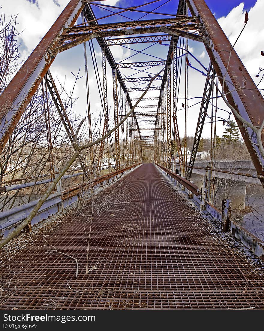 Old but not forgotten this neglected bridge structure still stands against the elements and seen against this blue sky. Old but not forgotten this neglected bridge structure still stands against the elements and seen against this blue sky