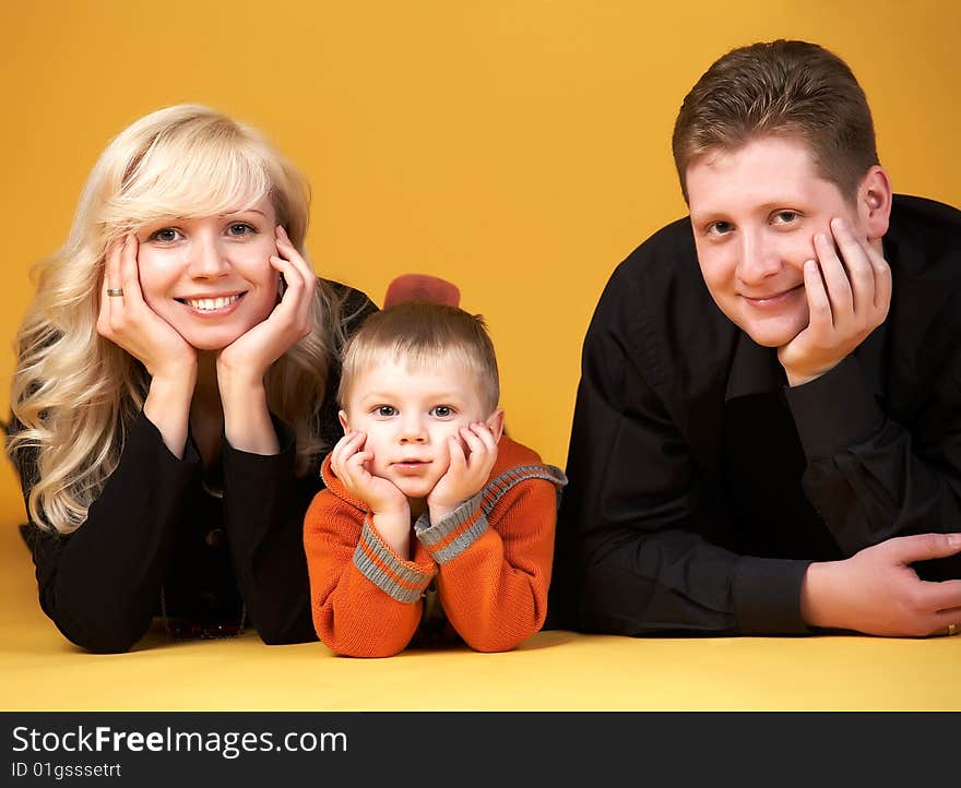 Happy family with baby on yellow background. Happy family with baby on yellow background