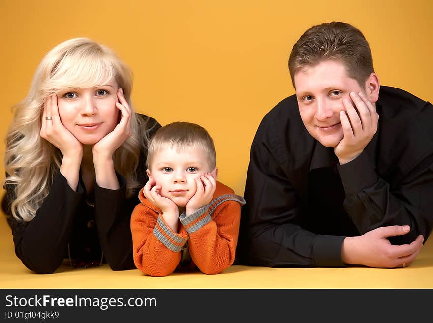 Happy family with baby on yellow background. Happy family with baby on yellow background