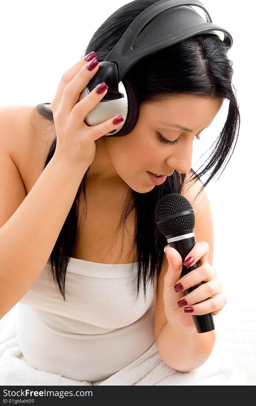 Top view of young female holding headphone and microphone against white background