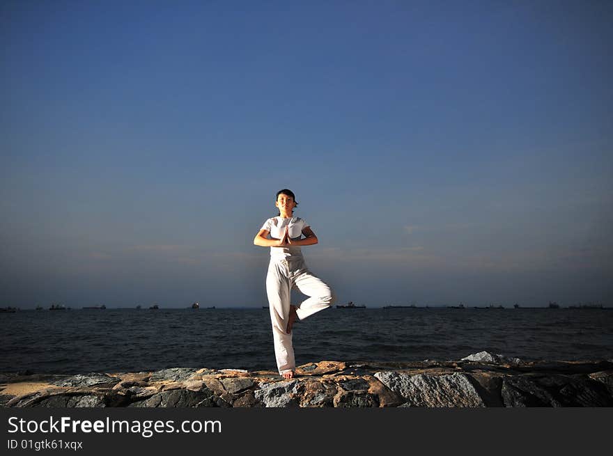 Picture of a woman doing yoga by the beach.