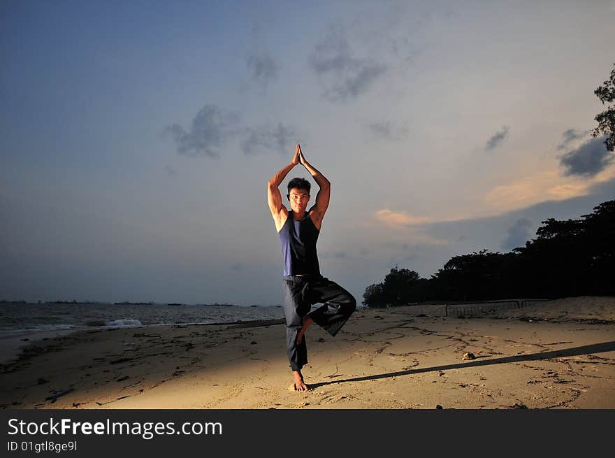 Picture of man doing yoga by the beach.