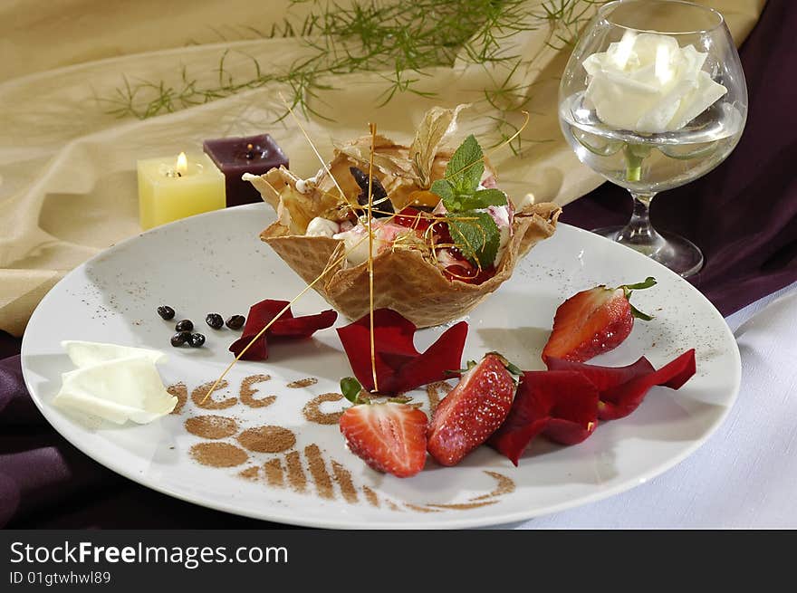 Frozen in a waffle basis, decorated a strawberry, mint and petals of roses