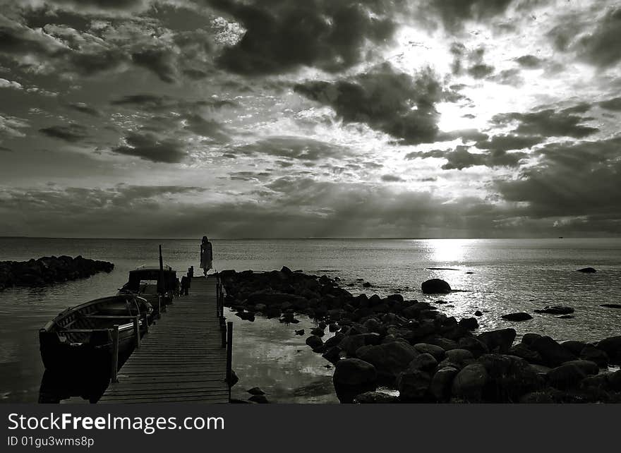 Sunset with a girl standing on a pier