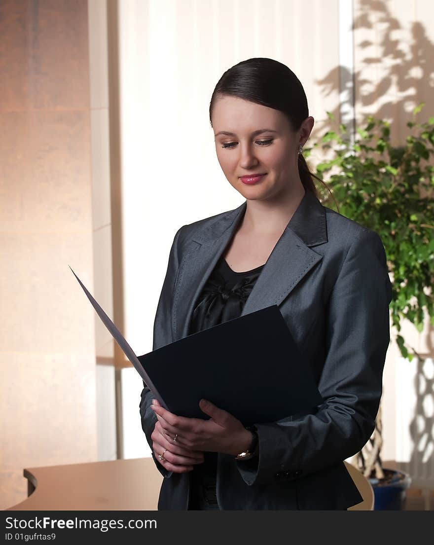 Portrait of a young attractive business woman with blue folder in a office environment. Portrait of a young attractive business woman with blue folder in a office environment