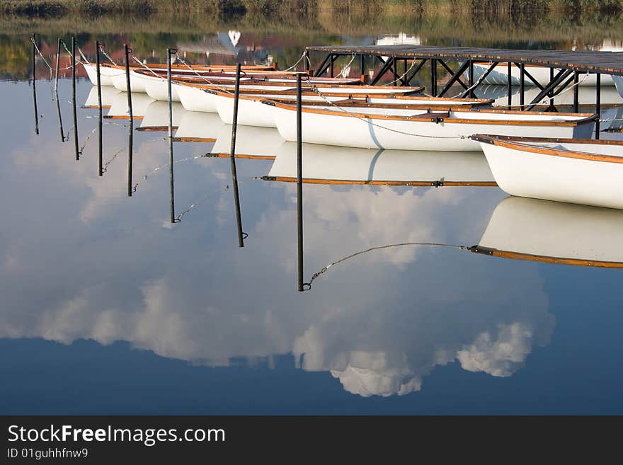 Water mirroring white boats and the cloudy sky.