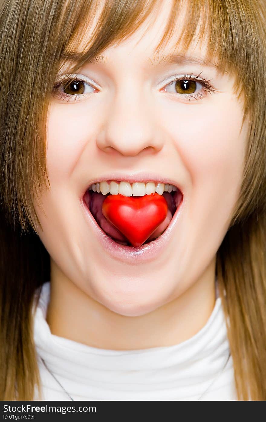 Young girl with heart-shaped candy in her mouth. Young girl with heart-shaped candy in her mouth