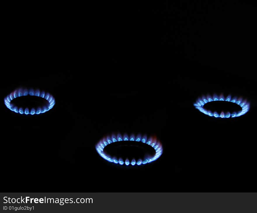 Blue flame of gas over black background