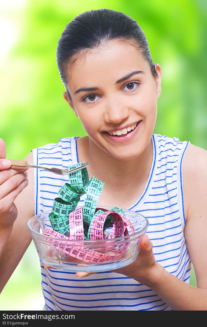 portrait of a young woman eating measuring tape with a fork. portrait of a young woman eating measuring tape with a fork