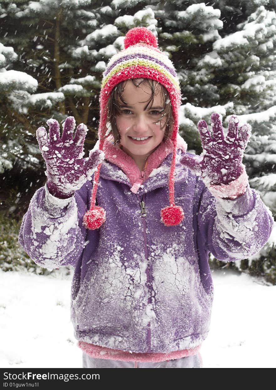 Young girl holding hands up while out playing in the snow. Young girl holding hands up while out playing in the snow