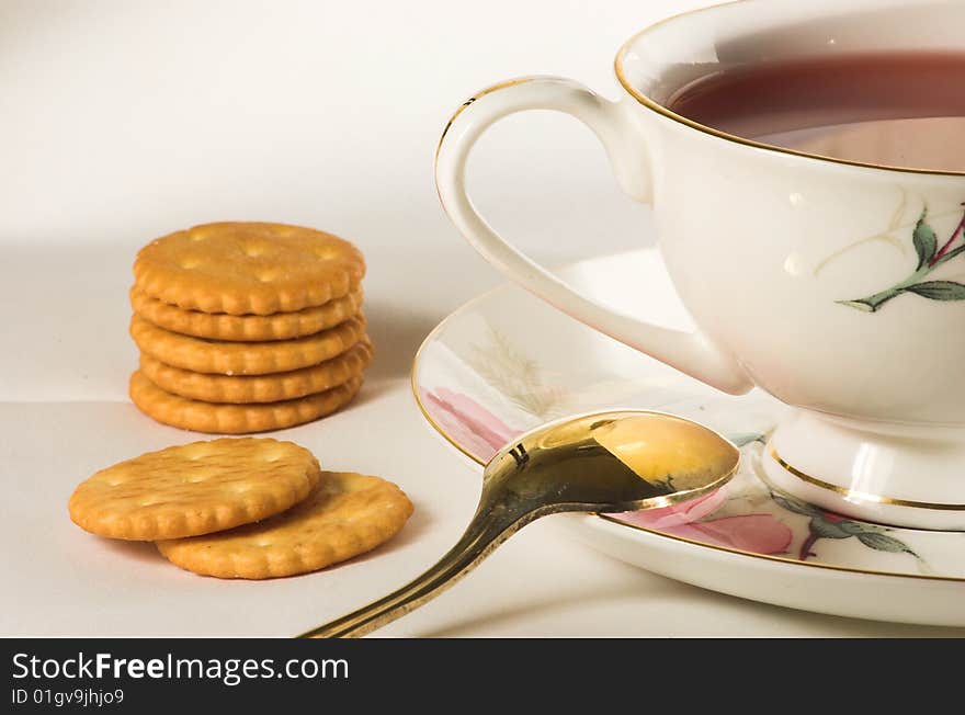 Drop of tea, gilded spoon and crackers on white table-cloth. Drop of tea, gilded spoon and crackers on white table-cloth