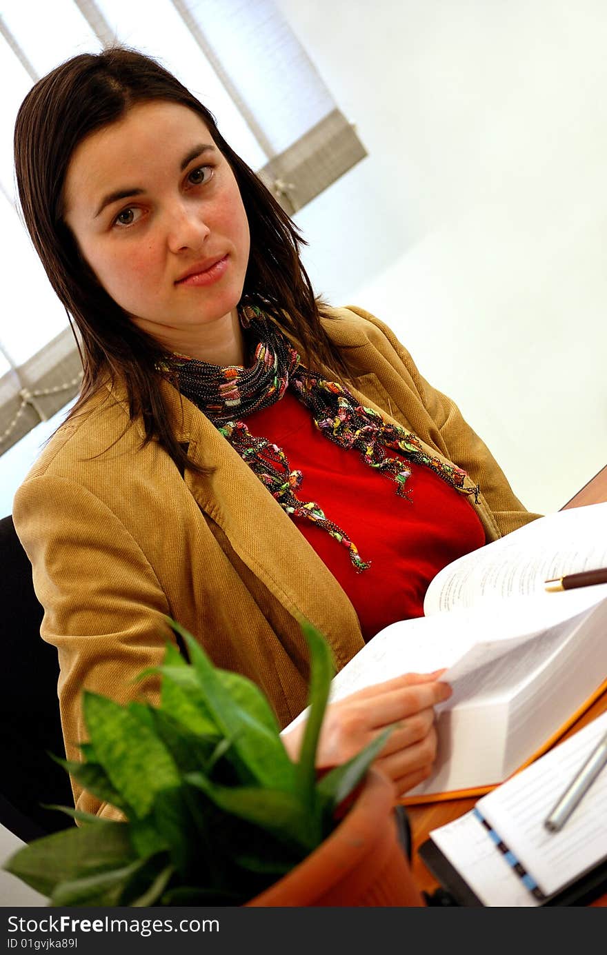 Young woman reading and studying at a busy desk