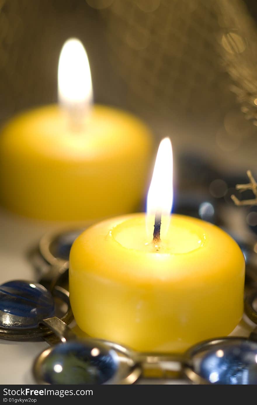 Yellow candle burns with  candles behind it.