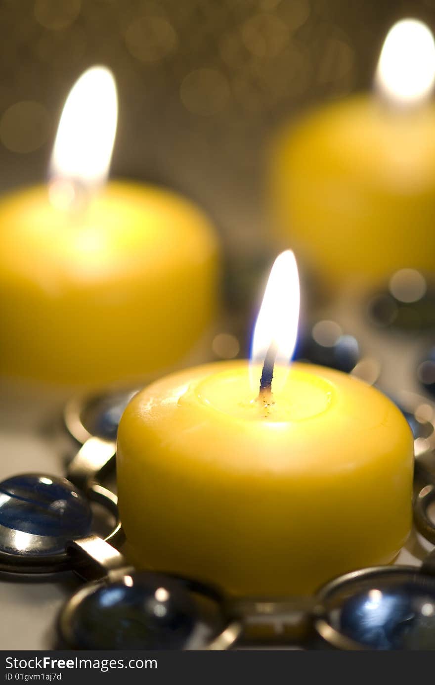 Yellow candle burns with  candles behind it.